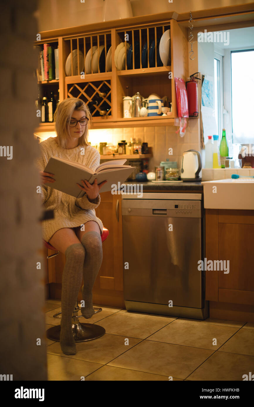 Frau liest ein Buch in der Küche zu Hause Stockfoto