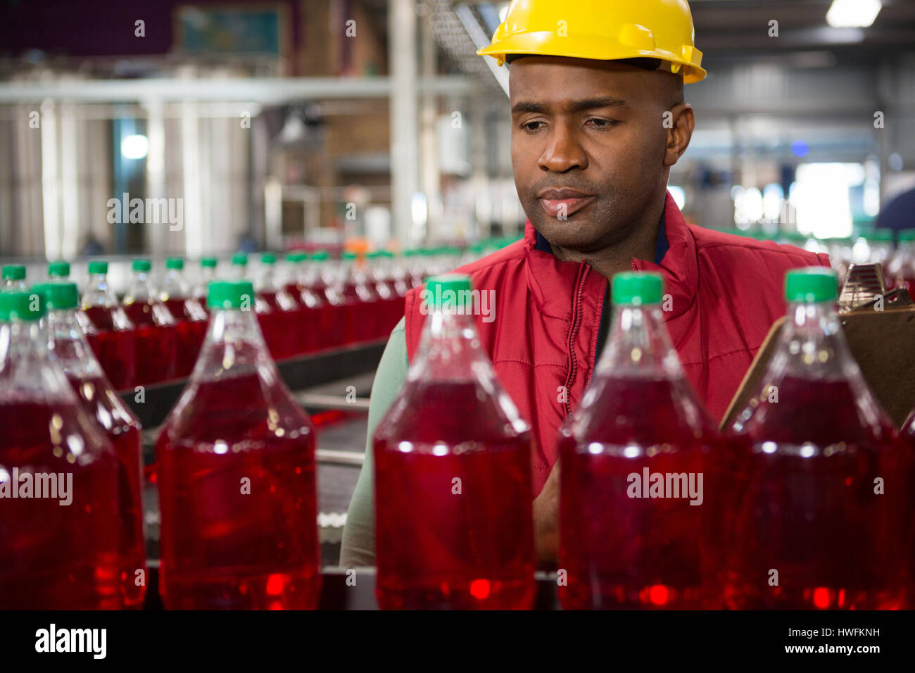 Schweren männlichen Arbeitnehmer Überwachung roten Saft Flaschen in Fabrik Stockfoto
