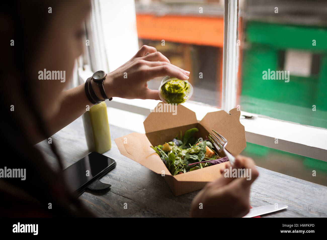 Frau, Gießen grünen Soße auf einen Salat in CafÃƒÂ © Stockfoto