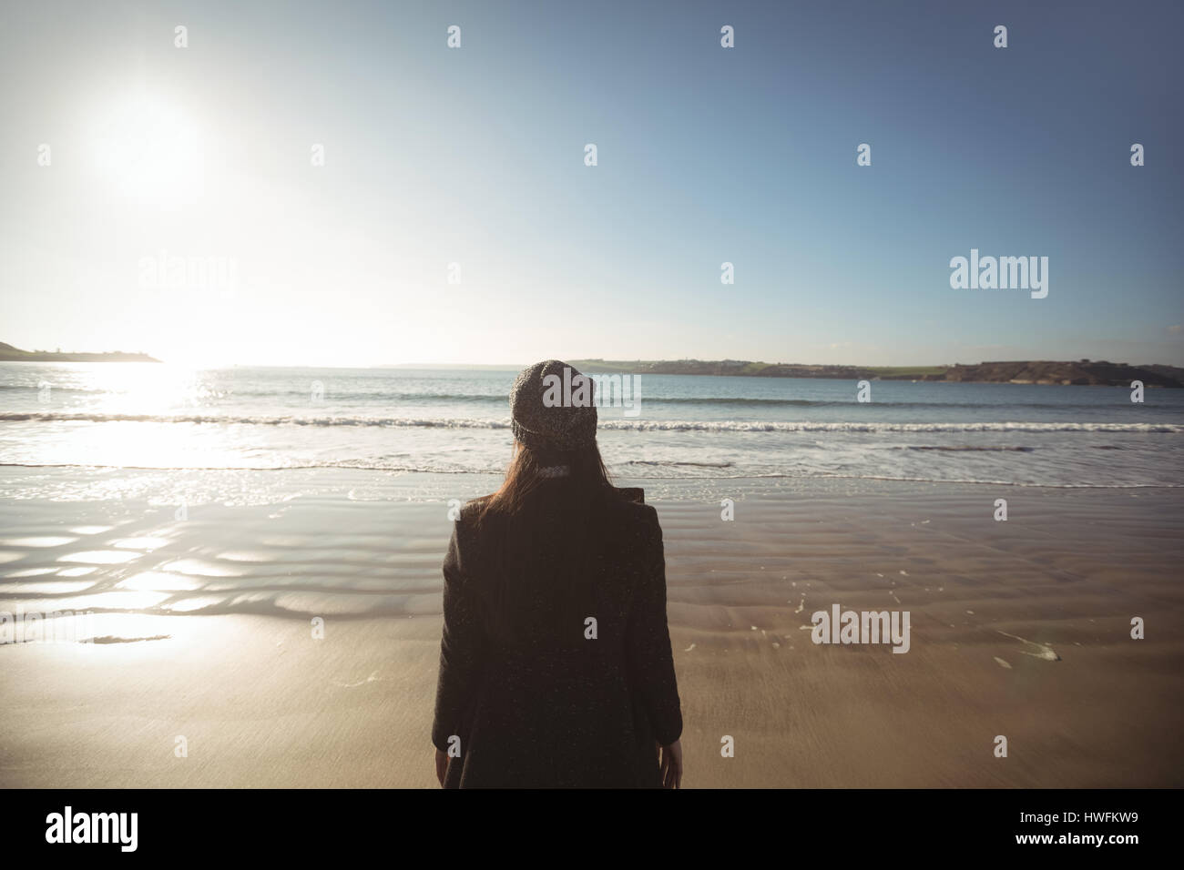 Rückansicht der Frau stehen am Strand tagsüber Stockfoto