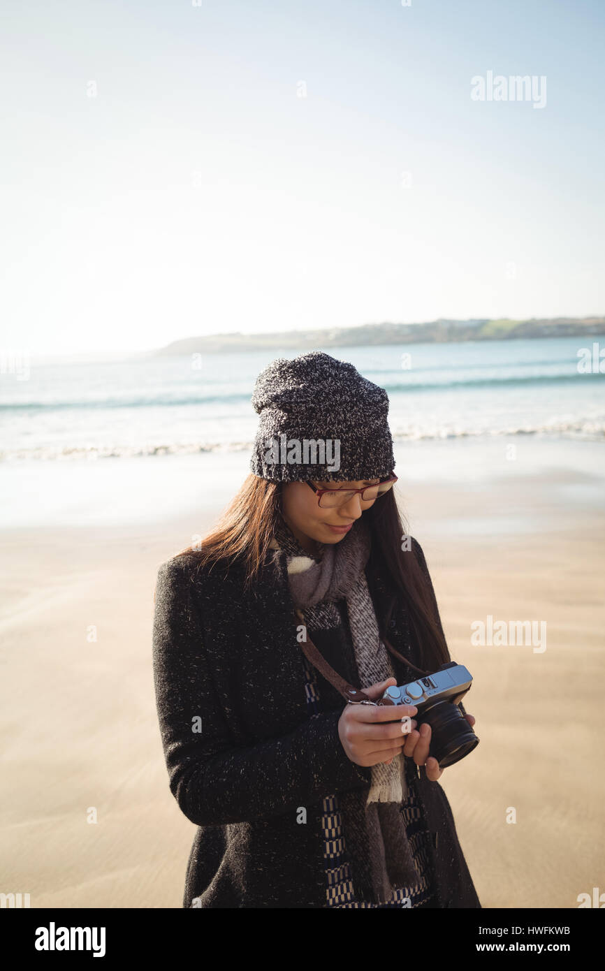 Frau mit Blick auf Fotos auf digitalen Kamera am Strand tagsüber Stockfoto