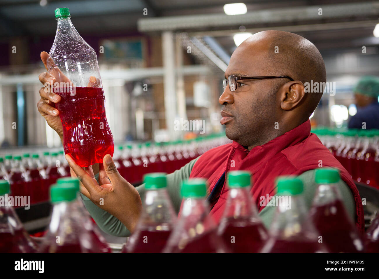 Schweren männlichen Arbeitnehmer Prüfung Flasche in kaltes Getränk Fabrik Stockfoto