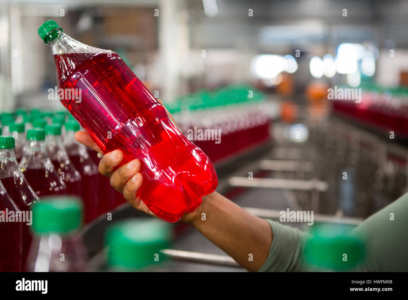 Hand des Arbeiters mit roten Saftflasche im Werk abgeschnitten Stockfoto