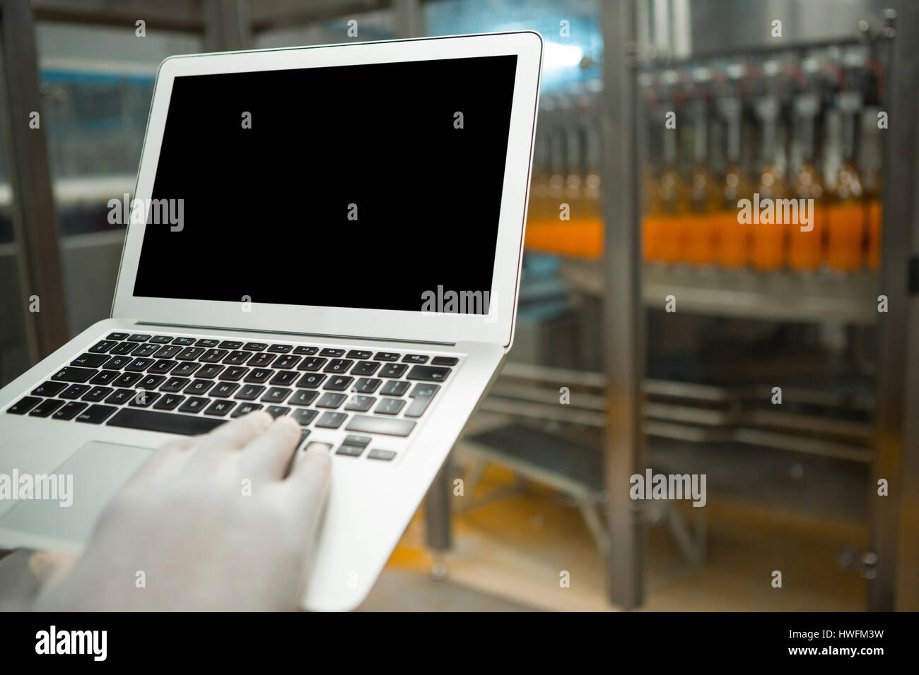 Abgeschnittenen Hand des Arbeiters mit Laptop in Fruchtsaft Fabrik Stockfoto
