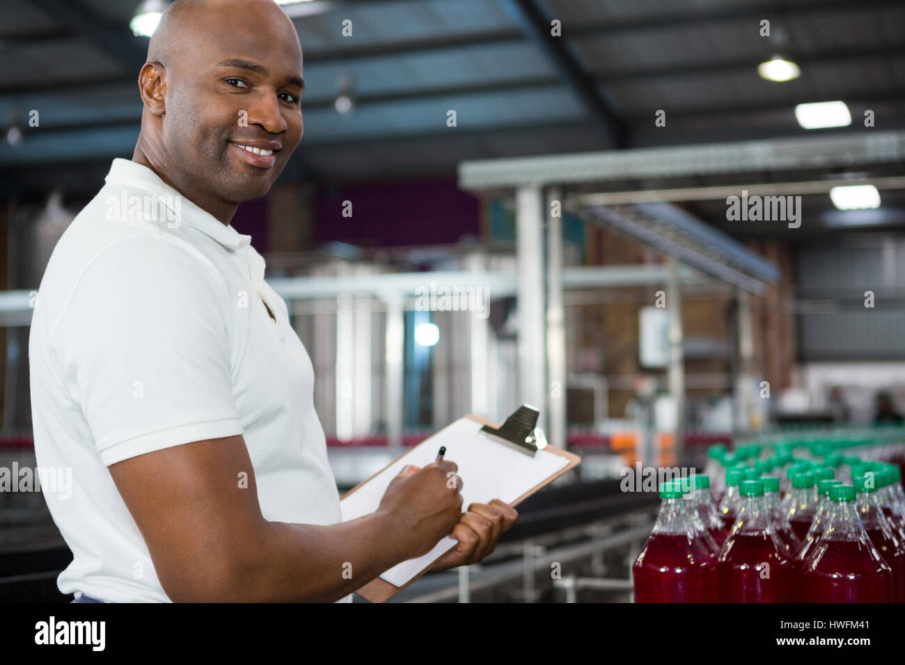 Porträt von lächelnden männlichen Arbeitnehmer über Produkte in Fruchtsaft Fabrik in Anbetracht Stockfoto