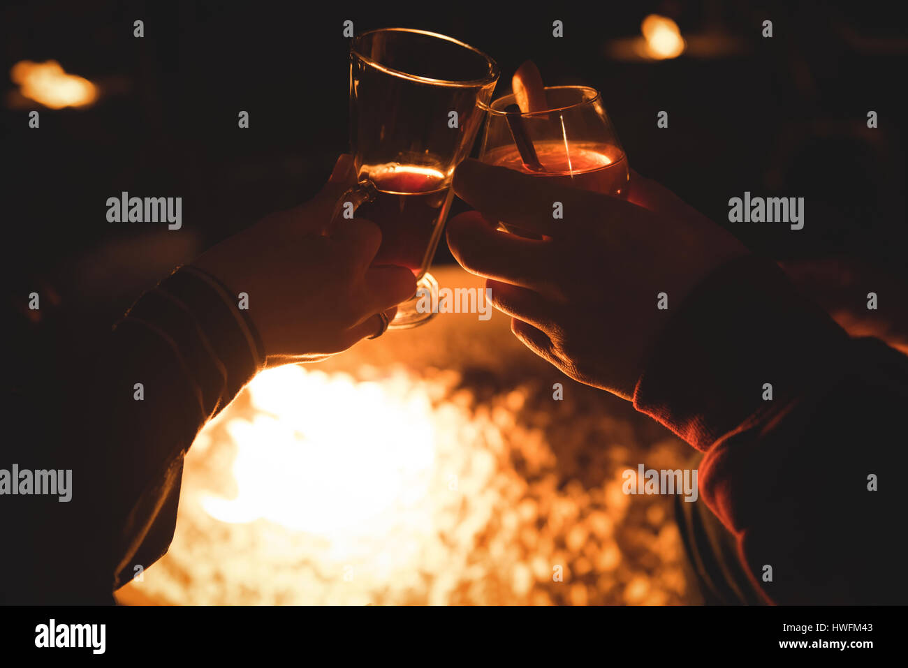 Hände des Paares hält Getränke gegen brennende Feuerstelle in der Nacht im Winter abgeschnitten Stockfoto
