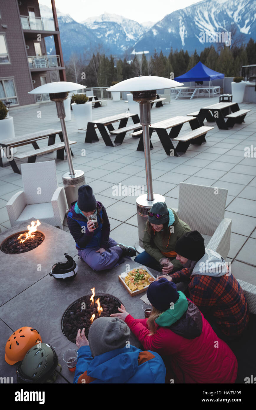Gruppe von Skifahrern reiben sich die Hände in der Nähe von Kamin im Skigebiet Stockfoto