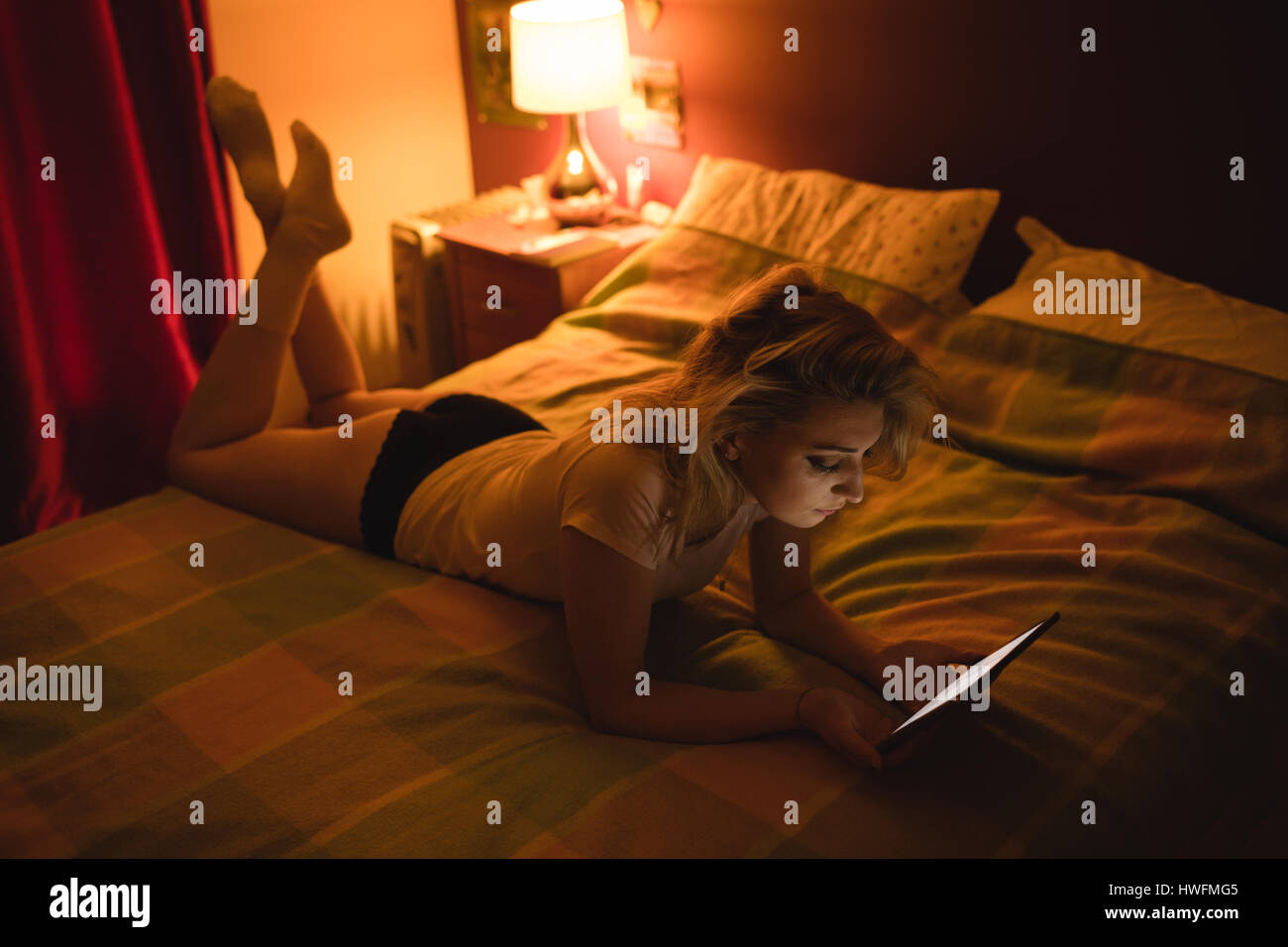 Frau liegend und mit digital-Tablette auf Bett im Schlafzimmer Stockfoto