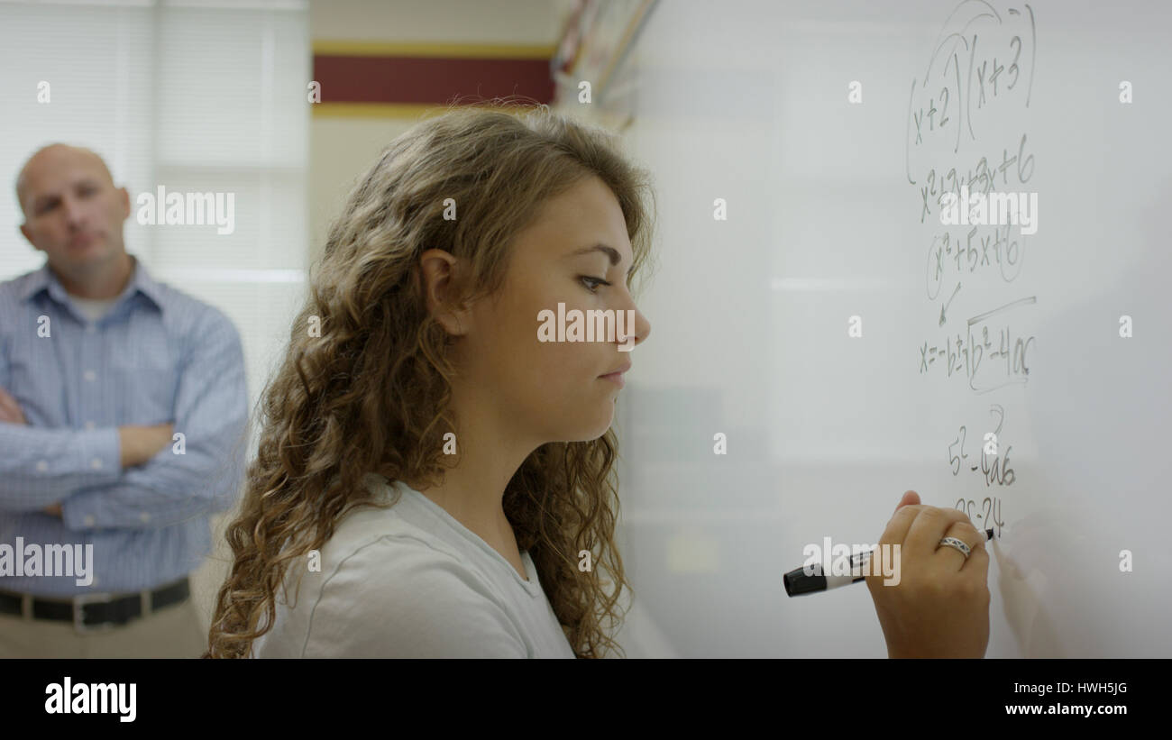 Höhenplan des Schülers schreiben mathematische Gleichung auf Tafel im Klassenzimmer Stockfoto