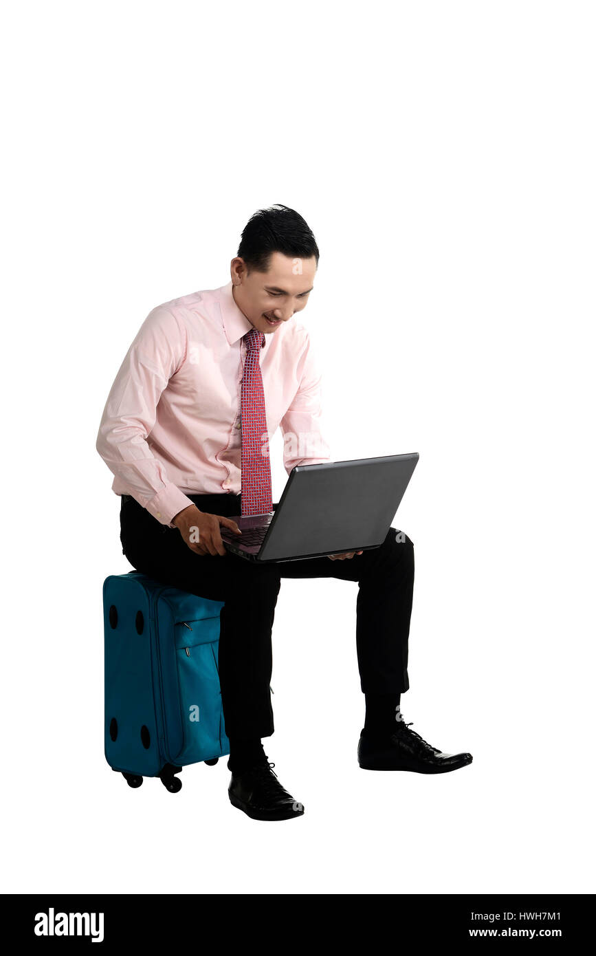 Mann sitzt auf dem Koffer arbeiten mit Laptop, isoliert auf weiß. Stockfoto