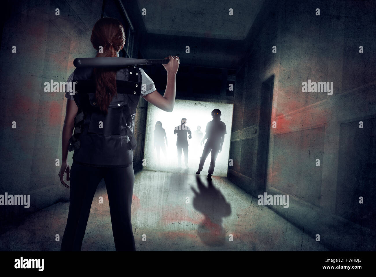 Junge Asiatin mit Baseballschläger auf ihrer Schulter gegen Zombie in einem Grunge-Gebäude Stockfoto