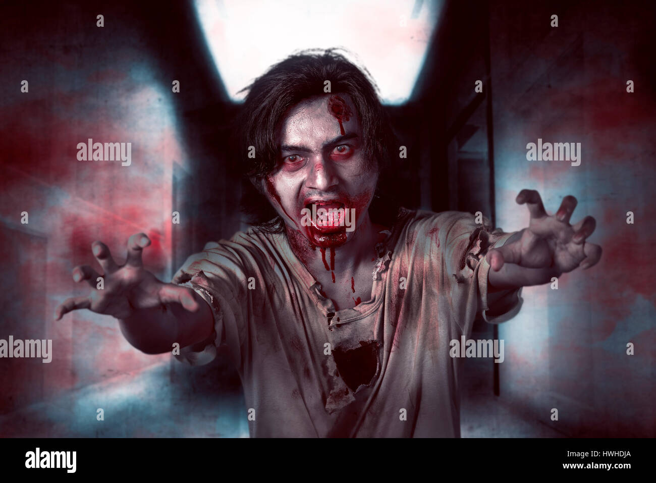 Asiatische Zombie Mann in den leeren Raum mit wütenden Ausdruck und Blut am Mund Stockfoto