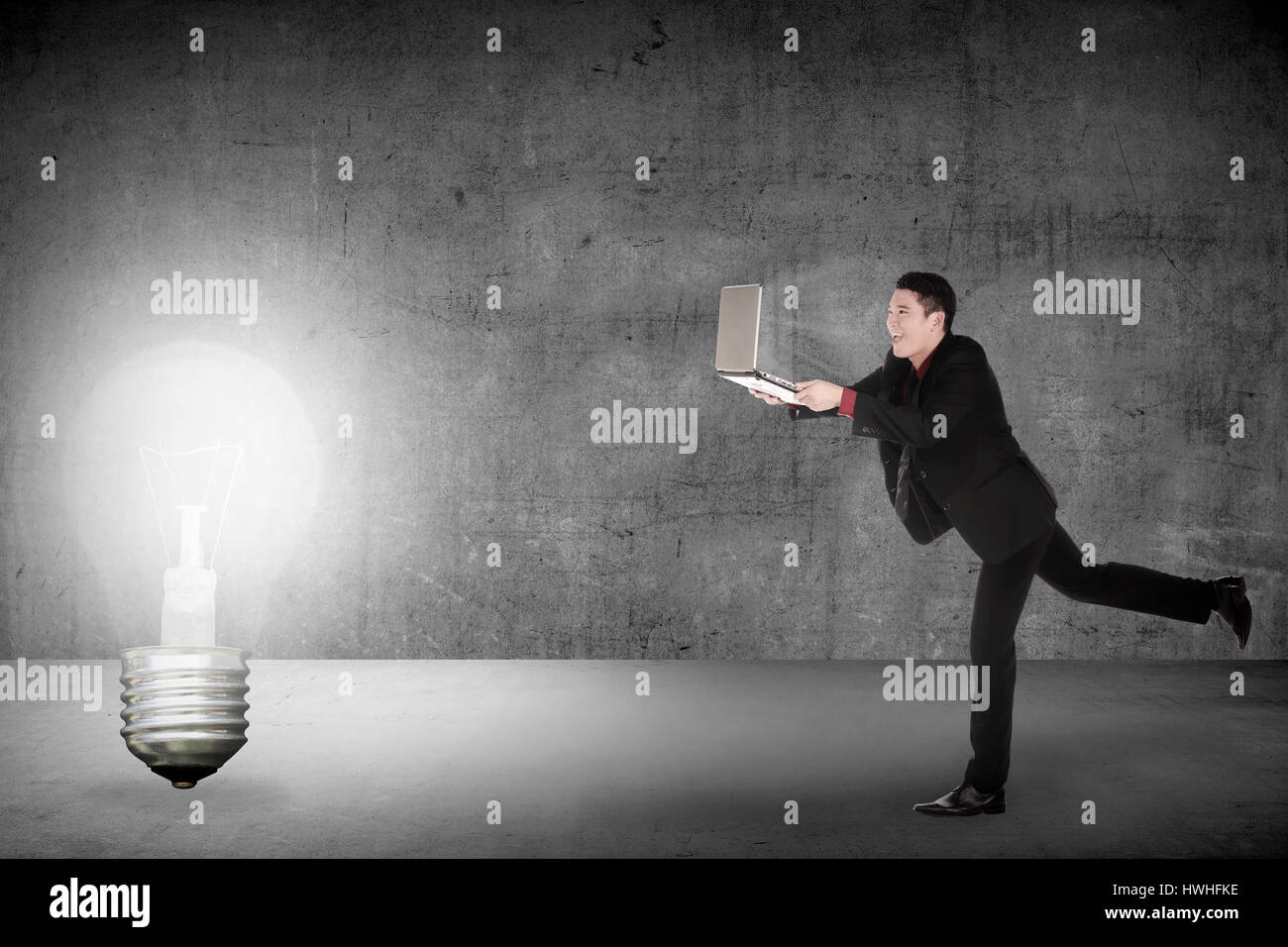Business-Mann laufen mit Laptop, die Glühbirne zu jagen. Konzeptionelle Idee zu machen Stockfoto