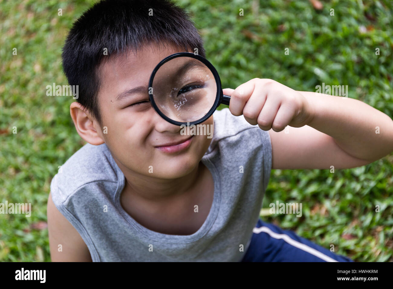 Gerne asiatische chinesische kleine Junge Blick durch die Lupe am Garten  Stockfotografie - Alamy