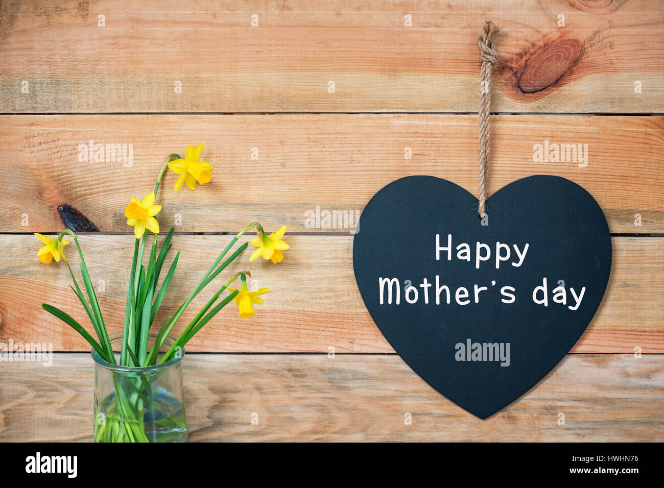 Glückliche Mütter-Tageskarte, Holzplanken mit Narzissen und einer Tafel in der Form eines Herzens Stockfoto