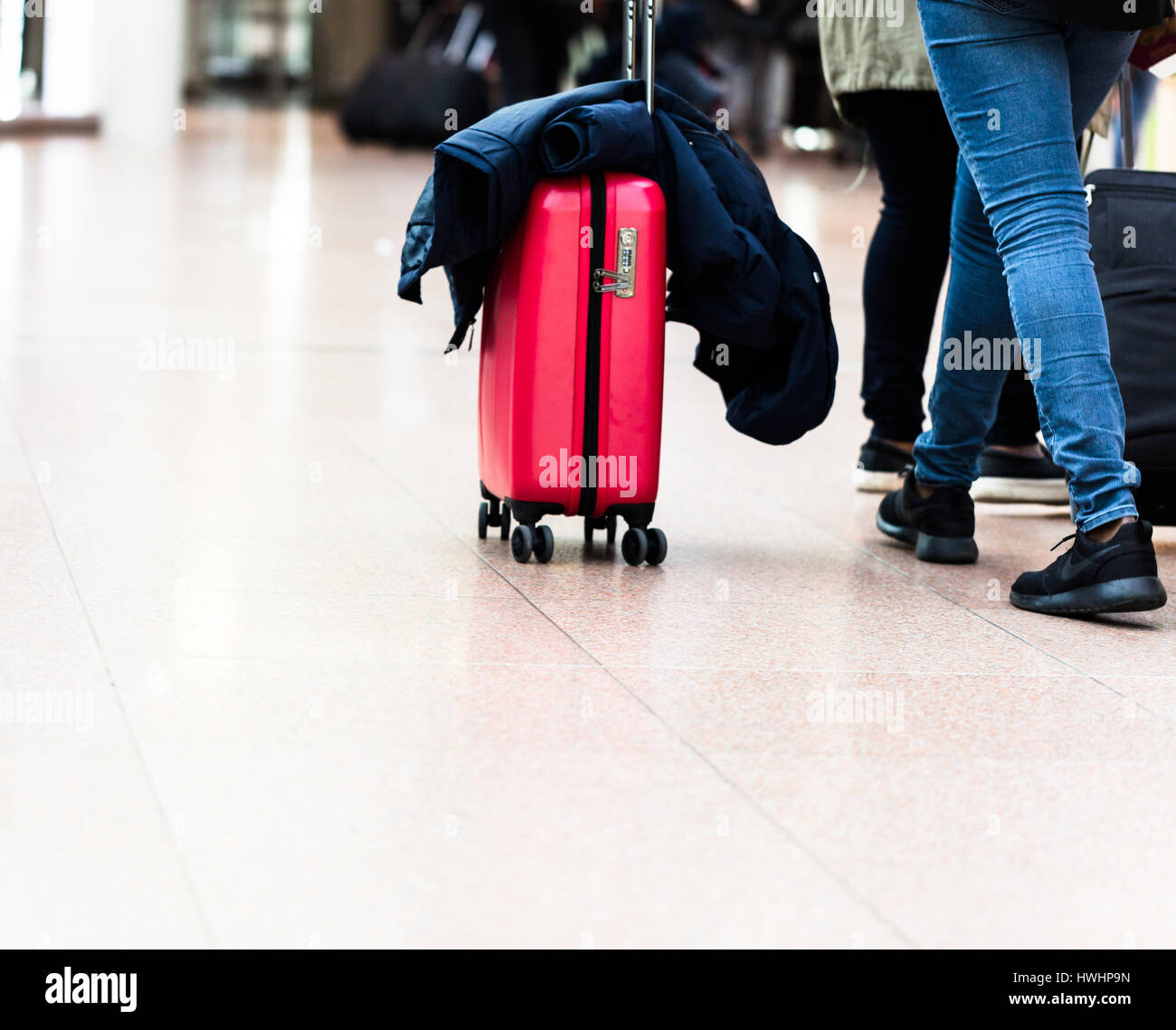 Junge Frau geht mit roten Gepäck im Flughafen-terminal. Echte Menschen. Niedrigen Winkel horizontale Ausrichtung. Stockfoto