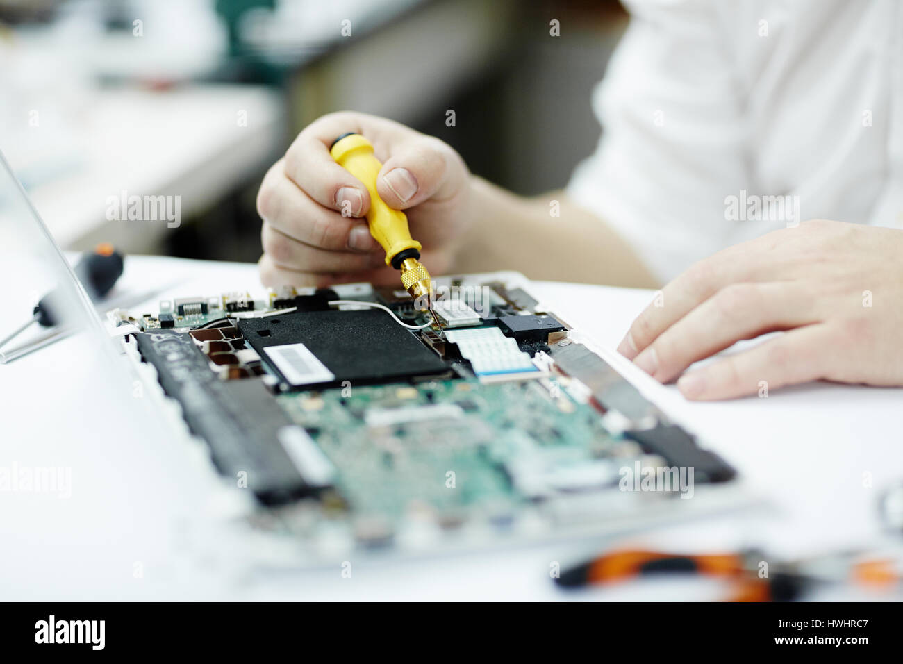 Closeup Aufnahme unkenntlich Mannes Montage der Leiterplatte im Laptop mit Schraubenzieher und verschiedene Werkzeuge auf Tisch in Werkstatt Stockfoto