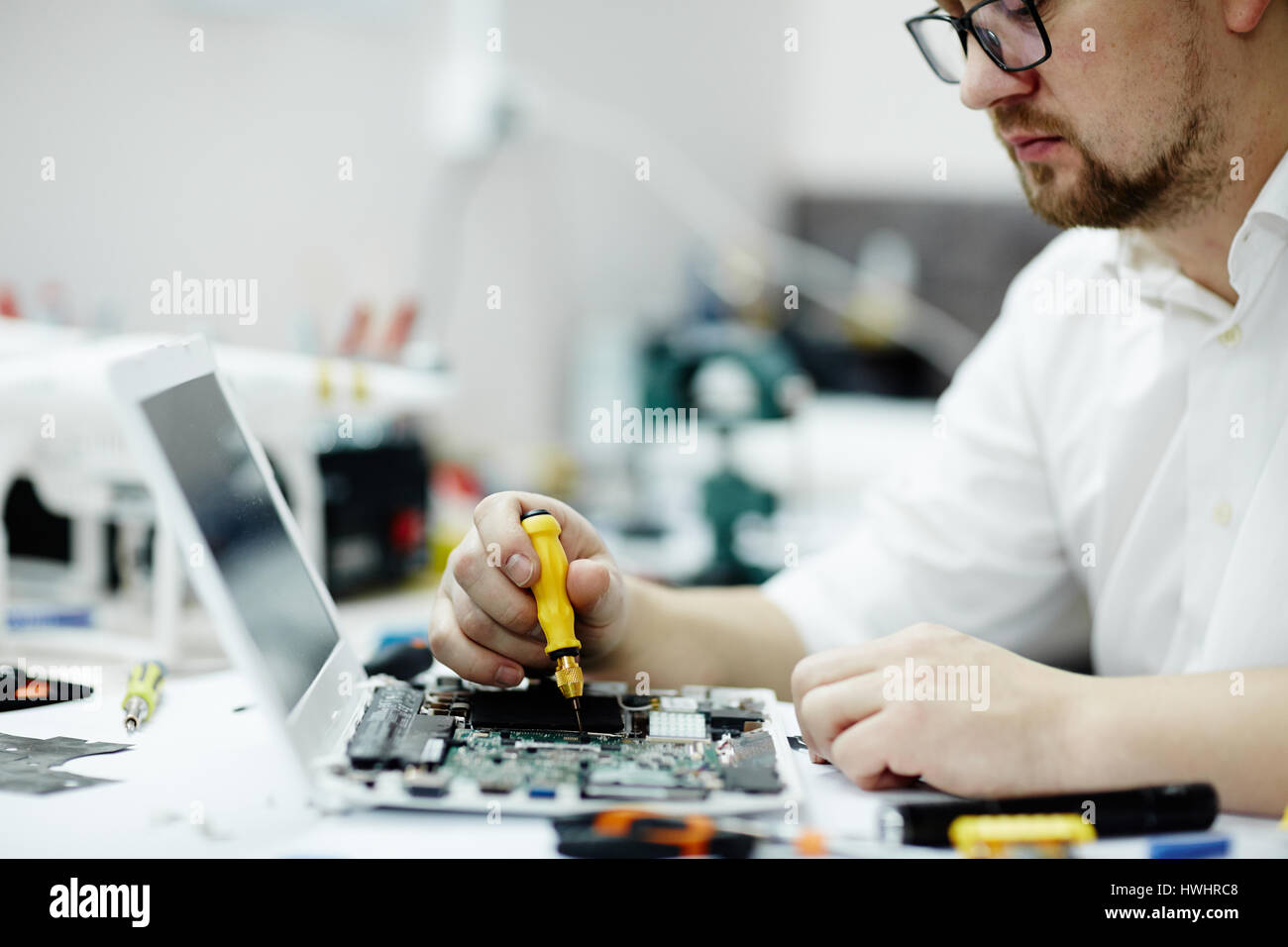 Porträt von modernen Arbeiten zur Montage von Leiterplatten mit Schraubenzieher und Werkzeuge auf Tisch in Werkstatt Stockfoto