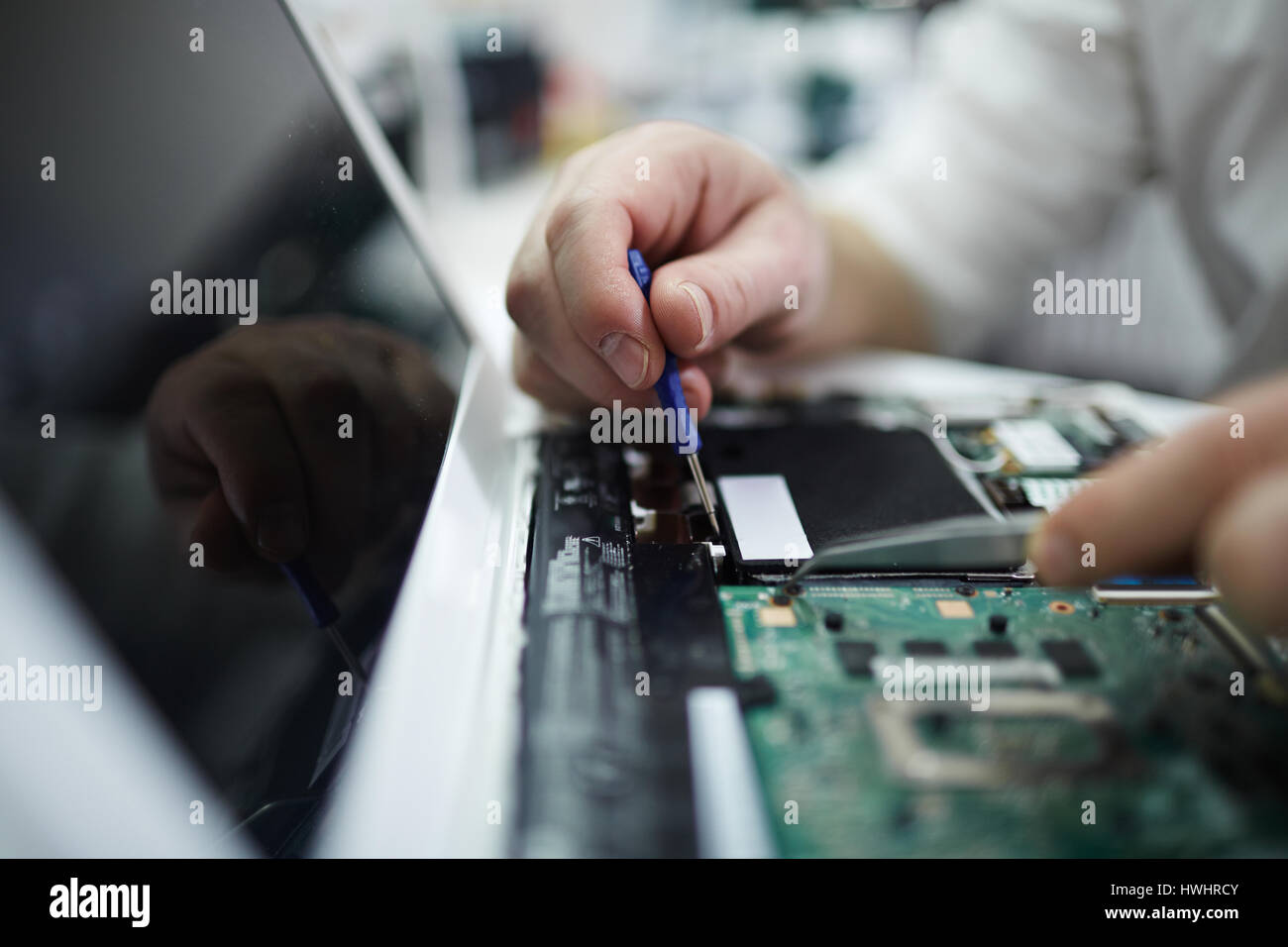 Closeup Aufnahme von männlichen Händen Reparatur Teile im Laptop mit Schraubenzieher und verschiedene Werkzeuge auf Tisch in Werkstatt Stockfoto