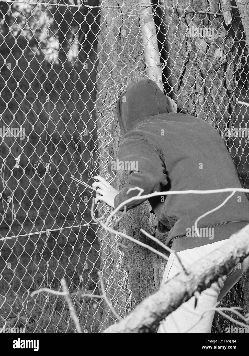 Person durch eine Öffnung mit der Hand festhalten an einem Stahldraht, schwarz und weiß, Australien 2016 Zaun zu kriechen Stockfoto