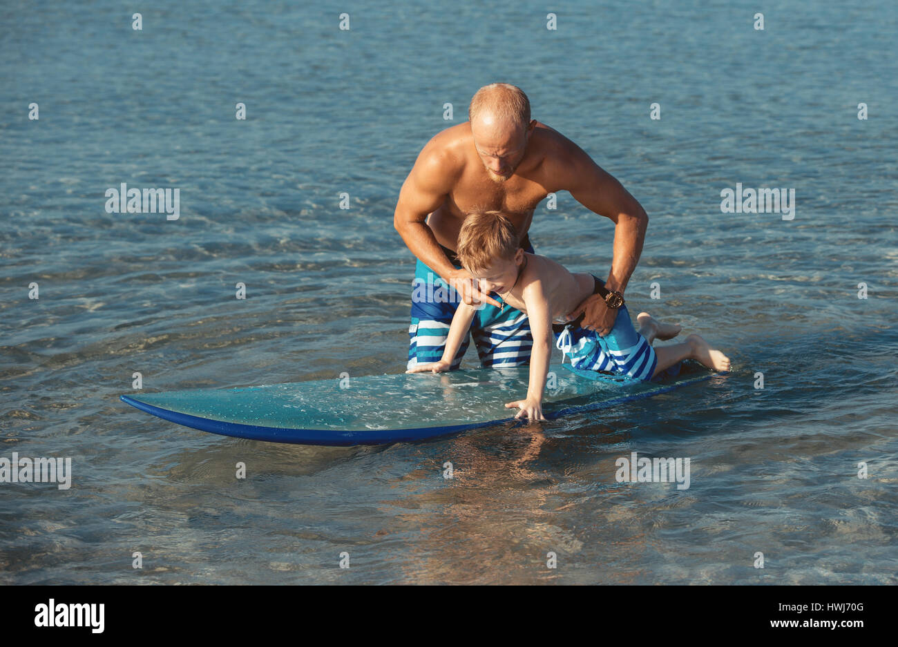 Sportlicher Mann mit kleinen Jungen lehrte ihn Surfen Stockfoto