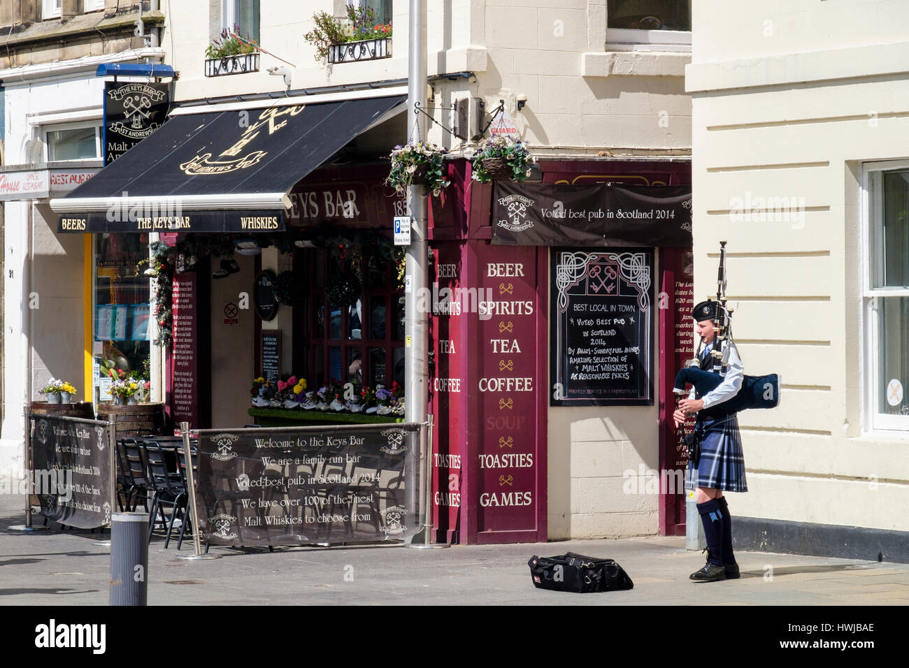Piper in Tracht spielt Dudelsack außerhalb der Schlüssel Bar Inn im Stadtzentrum. Market Street, Royal Burgh St Andrews, Fife, Schottland Stockfoto
