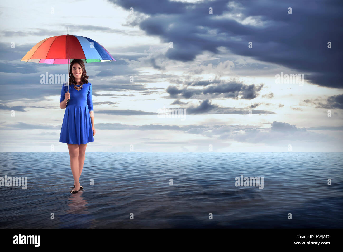 Frau mit bunten Regenschirm mitten im Ozean Stockfoto