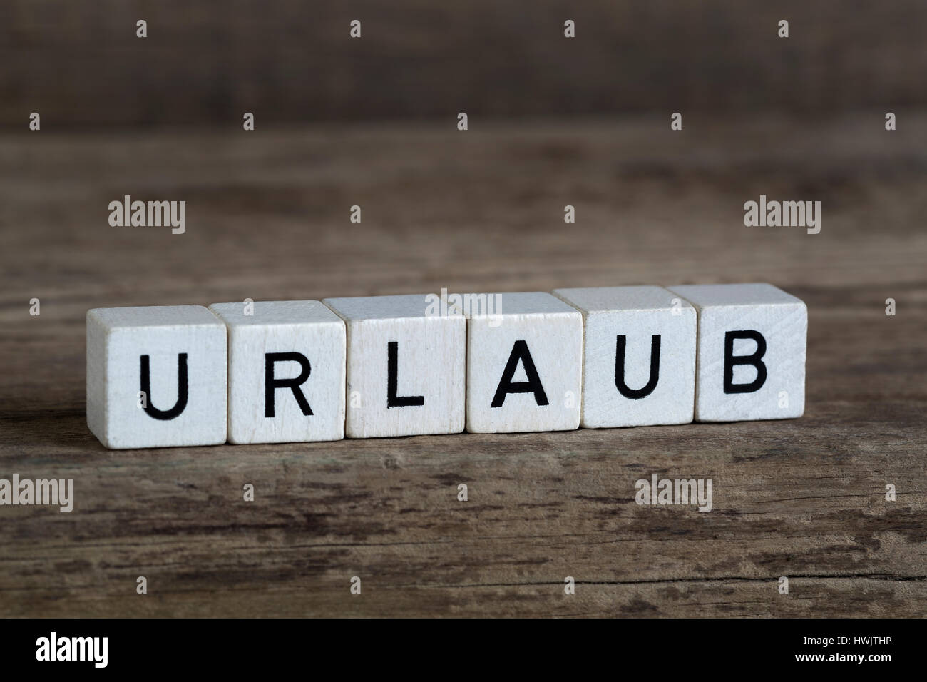 Deutsches Wort Urlaub, geschrieben in Würfeln auf einem hölzernen Hintergrund Stockfoto