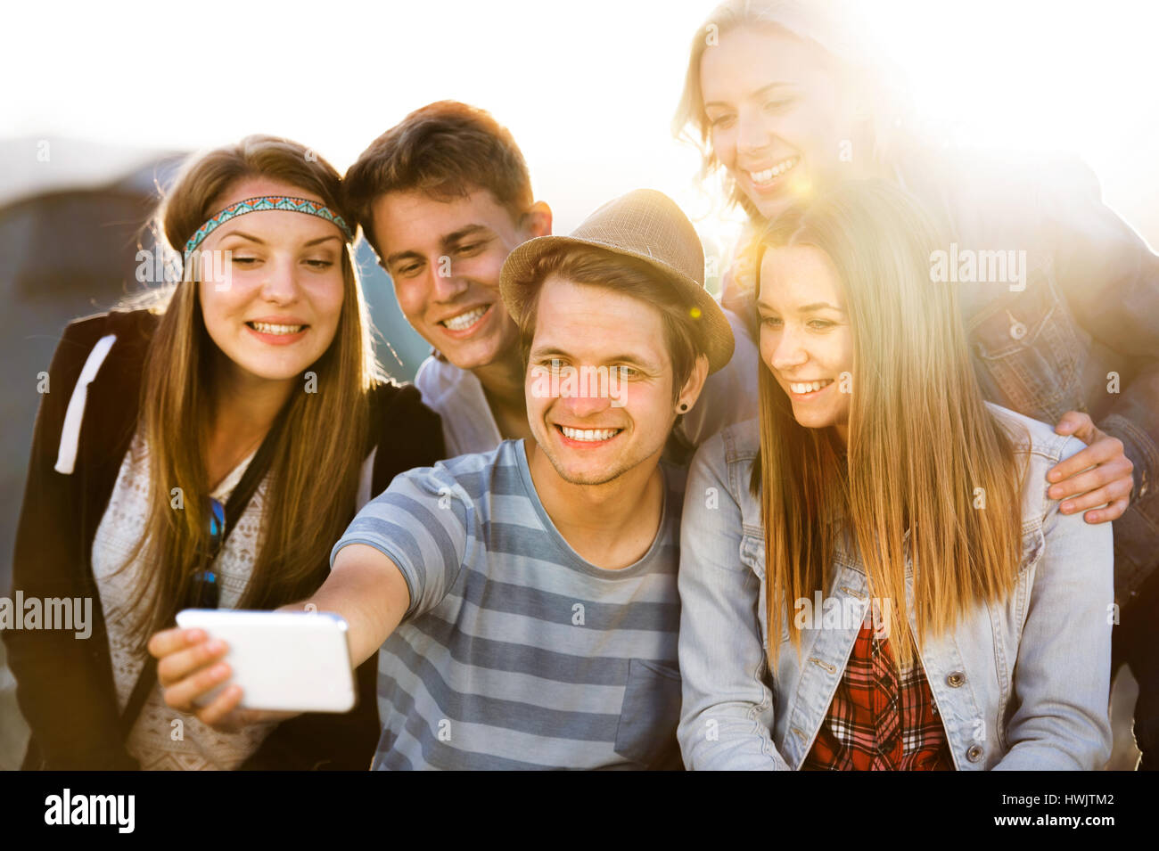 Gruppe von Teenager-Jungen und Mädchen im Sommer-Musik-Festival, auf dem Boden sitzend, die Selfie mit Smartphone Stockfoto