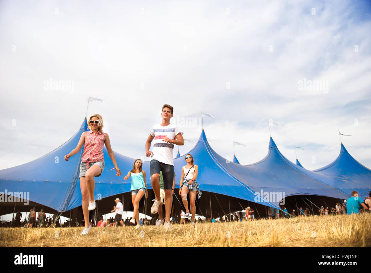 Gruppe von Teenager-Jungen und Mädchen im Sommer-Musikfestival zu Fuß vor der große blaue Zelt, sonnigen Tag Stockfoto