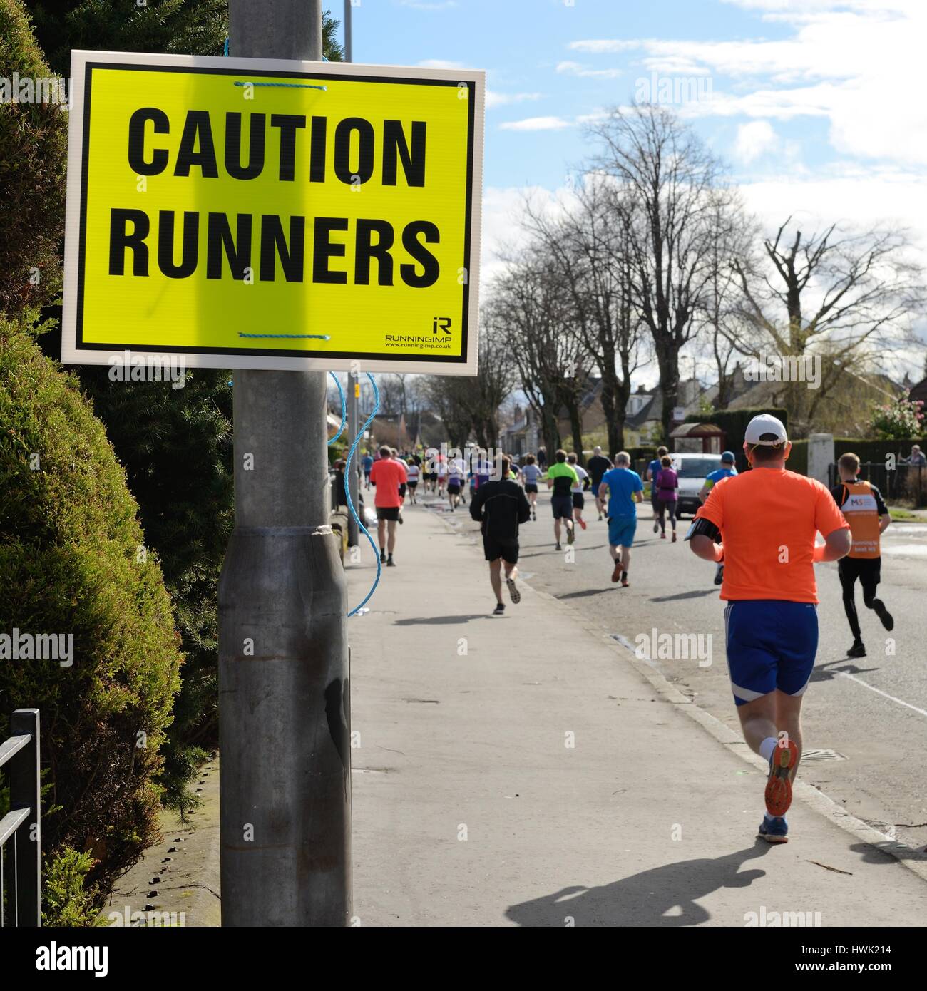 Ein Schild warnt Verkehr von Läufern auf öffentlichen Straßen während der Alloa Halbmarathon in Schottland, Großbritannien Stockfoto