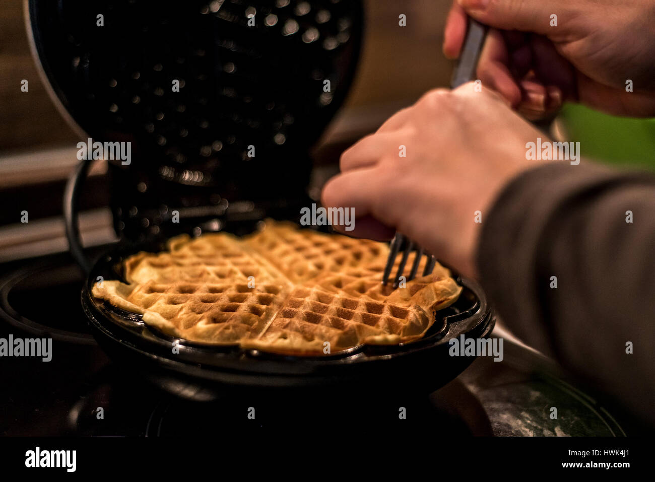 Hausgemachte Waffeln werden in einem Waffeleisen zubereitet. Stockfoto