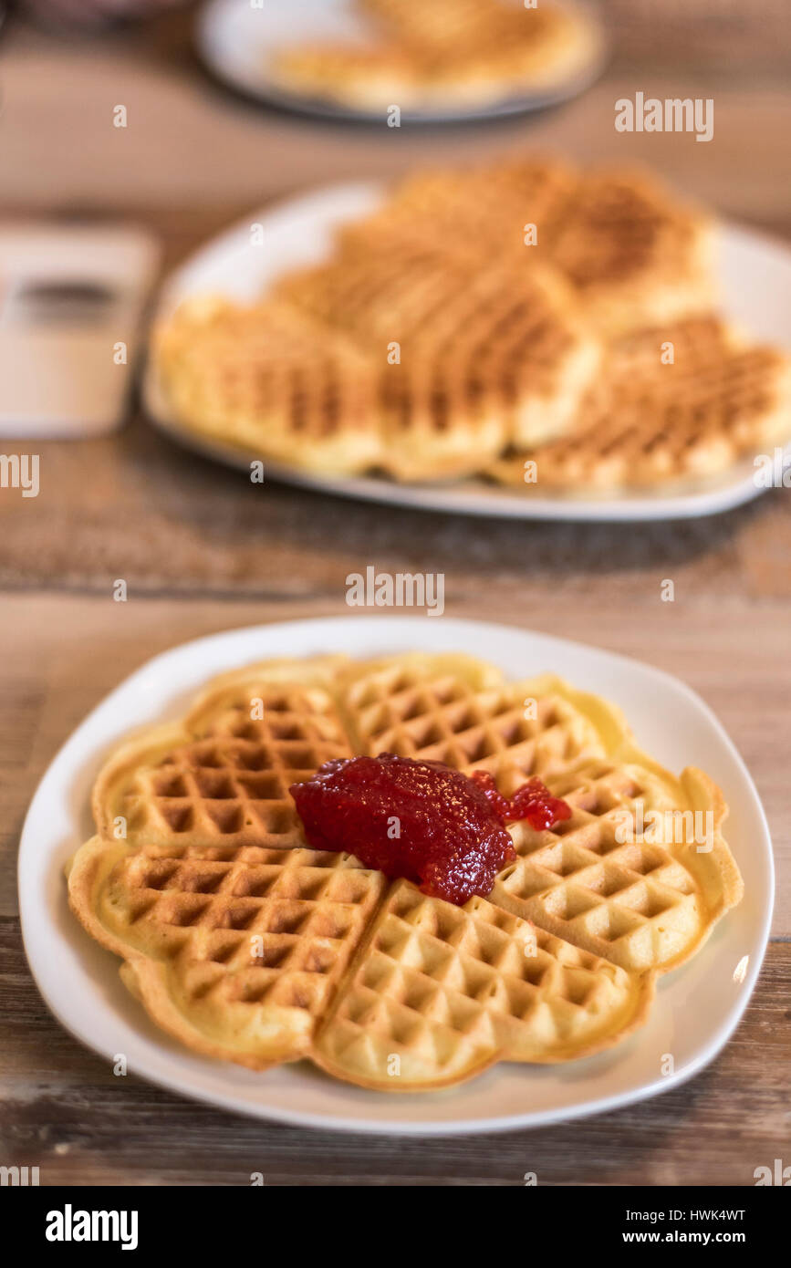 Essen hausgemachte Waffeln auf einem weißen Teller mit roten Erdbeer-Marmelade-Gelee Stockfoto