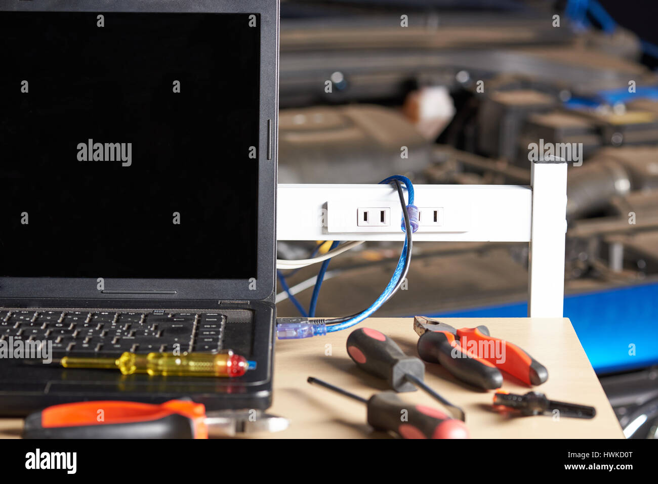 Tabelle mit Werkzeugen für Autocomputer Diagnose auf unscharfen Fahrzeug Haube Hintergrund. Stockfoto