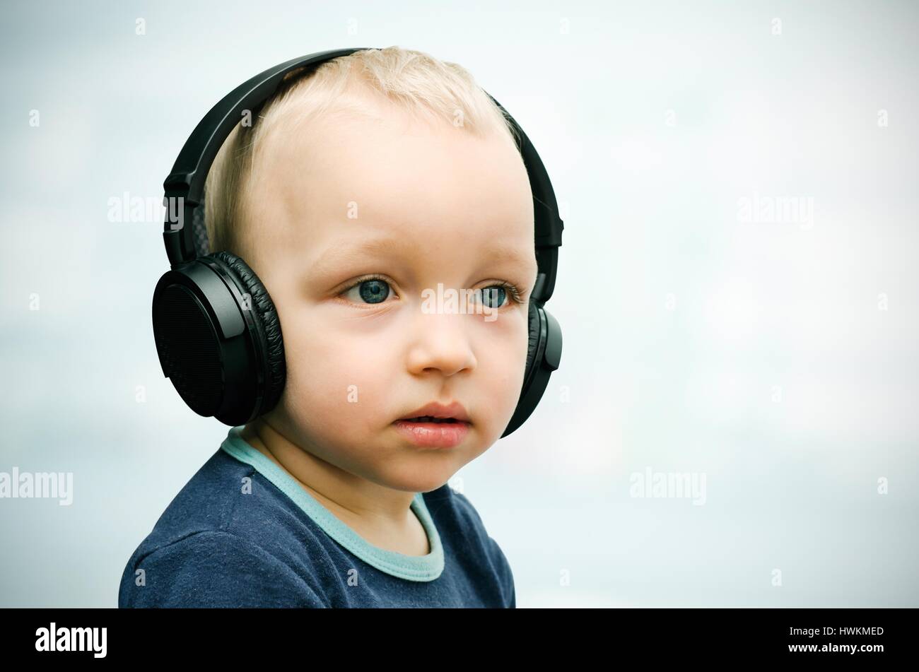 kleiner Junge hört Musik über drahtlose Kopfhörer Stockfoto