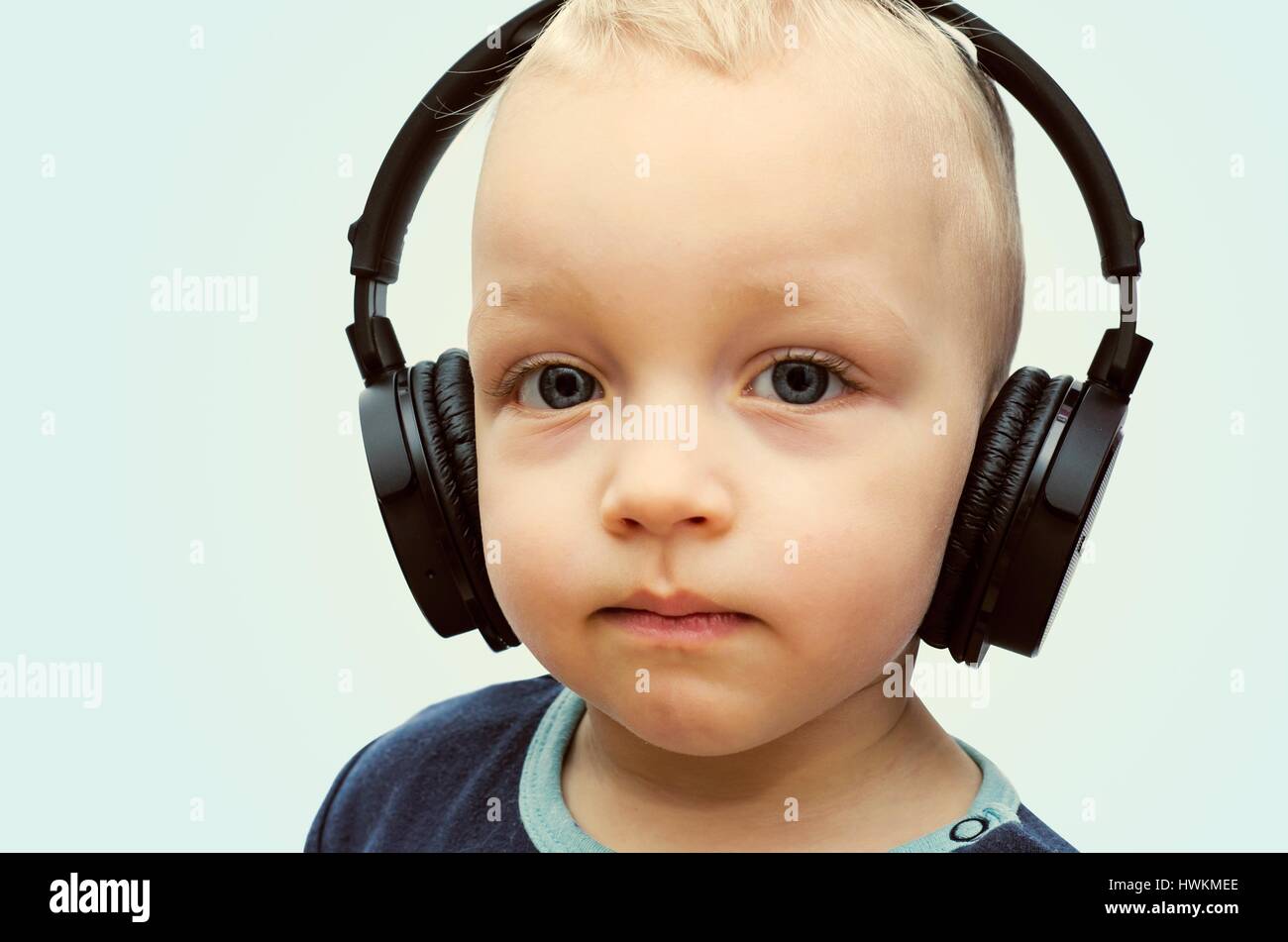 kleiner Junge hört Musik über drahtlose Kopfhörer Stockfoto