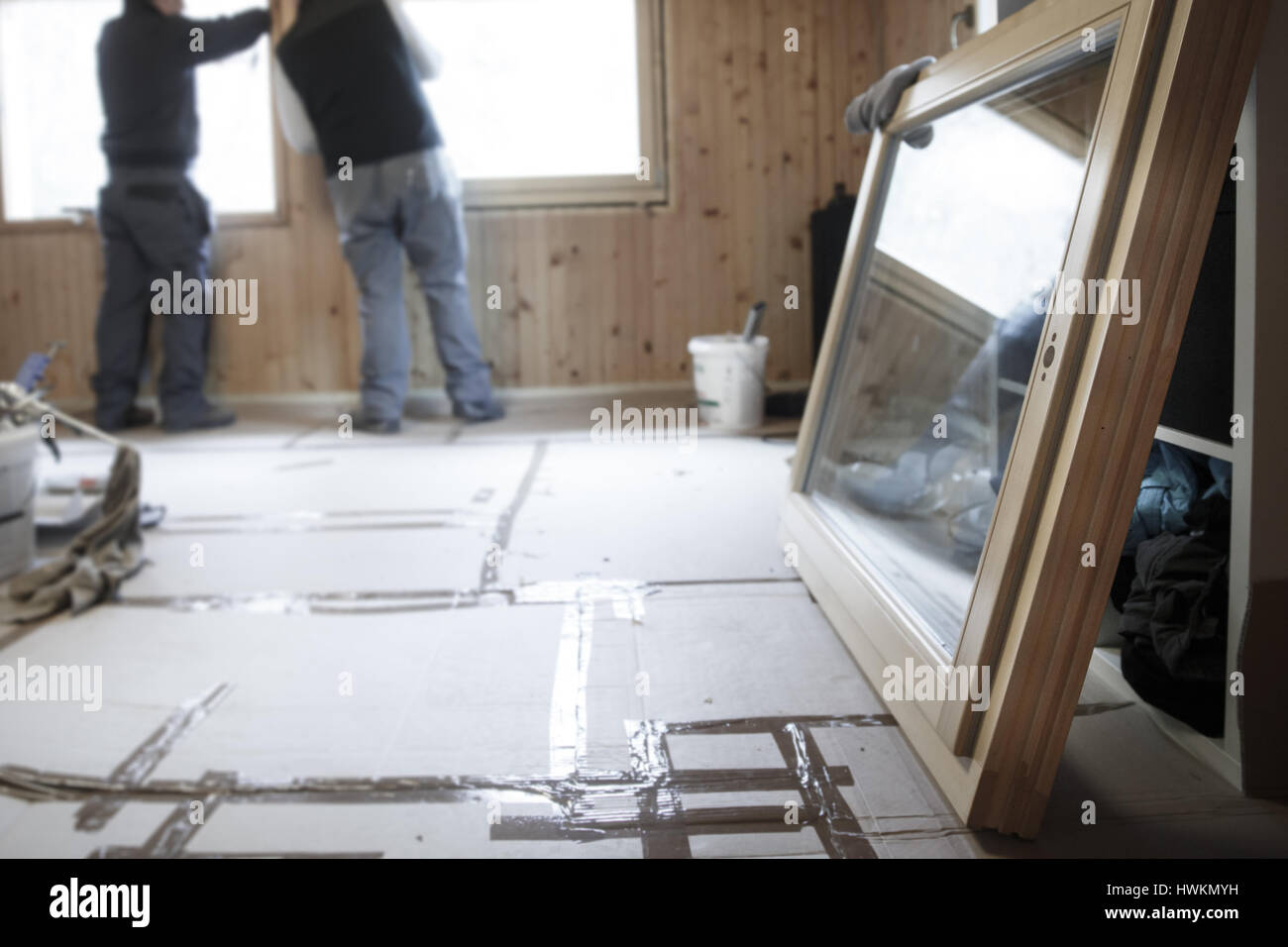 Arbeiter im Hintergrund installieren neu, drei Fenster aus Holz Fenster in einem alten Holzhaus mit einem neuen Fenster in den Vordergrund. Renovierungs, sust Stockfoto