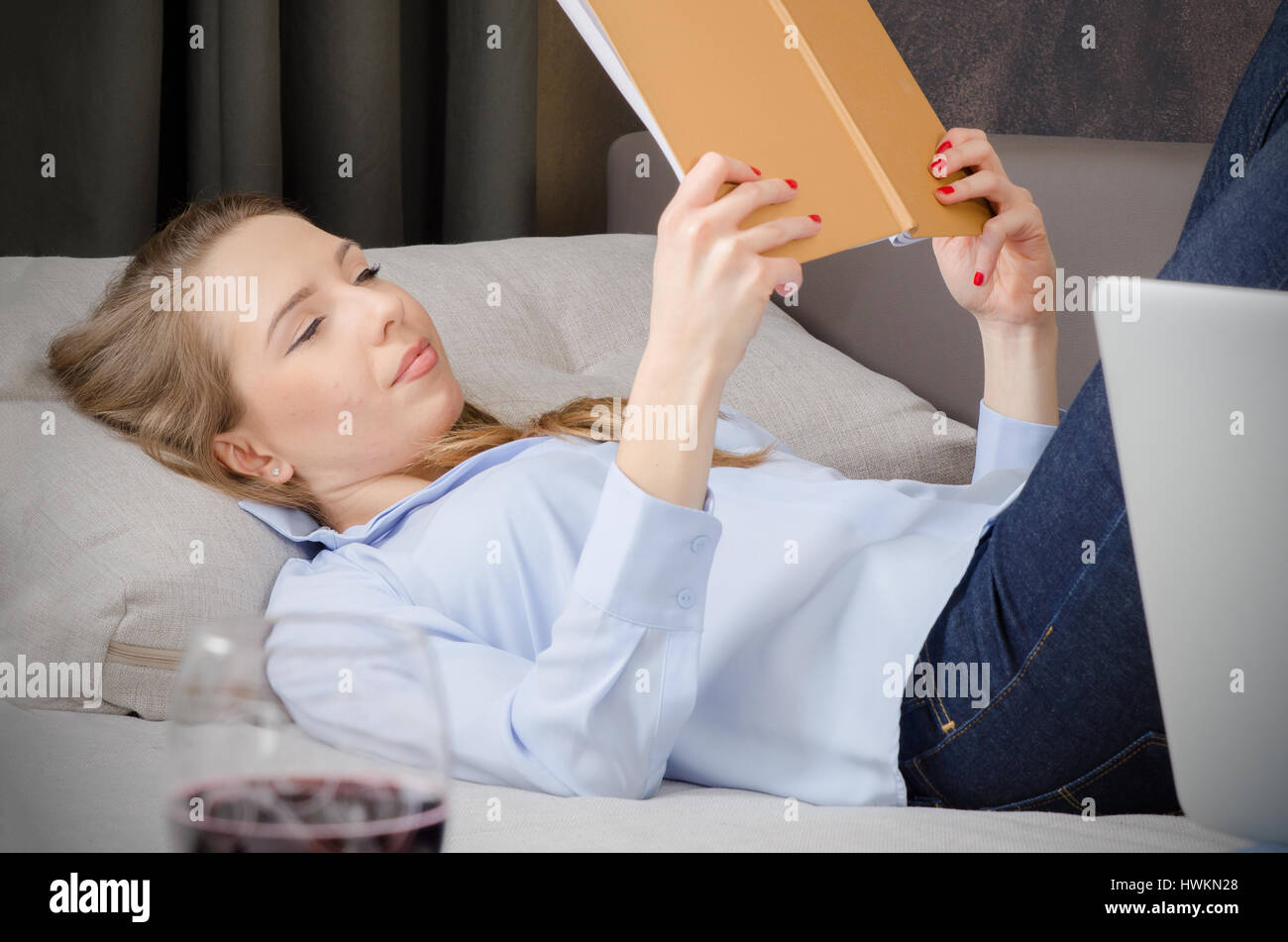 Frau, Verlegung auf Sofa und ein Buch zu lesen. Buch lesen Sie Frau Verlegung Sofa entspannen Lesung genießen Sie Konzept Stockfoto