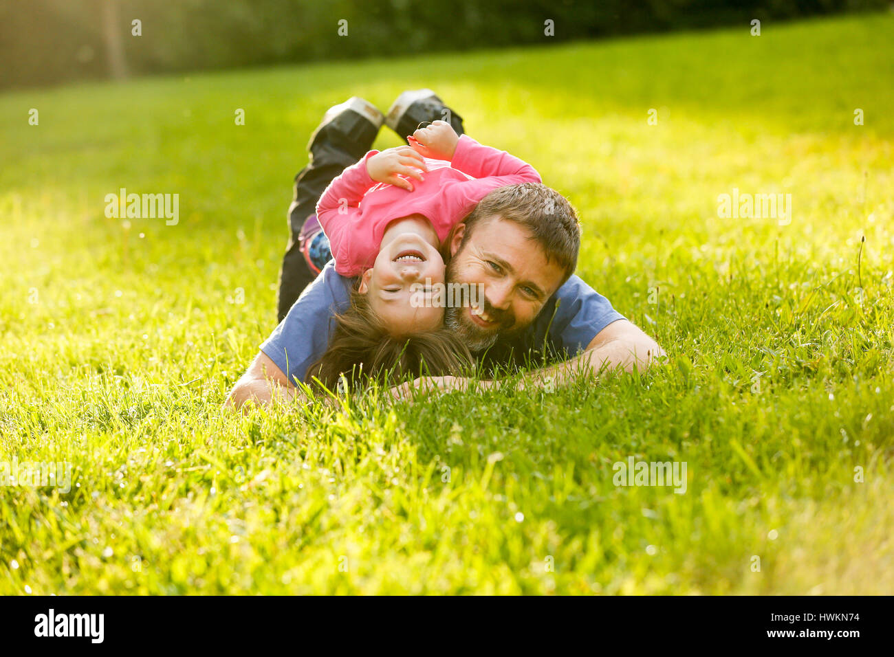 Vater und Tochter liegen auf dem Rasen, genießen jede andere Firma, bonding, spielen, Spaß in der Natur an einem hellen, sonnigen Tag gewidmet. Elternschaft, l Stockfoto