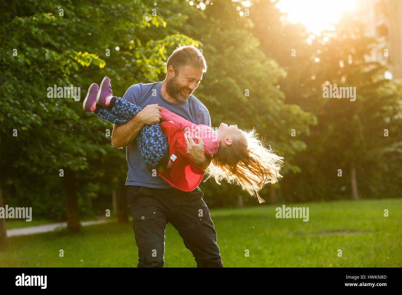 Vater seiner Tochter im Kreise drehen, kleben, spielen, Spaß in der Natur an einem hellen, sonnigen Tag gewidmet. Elternschaft, Lebensstil, Erziehung, Kinder Stockfoto
