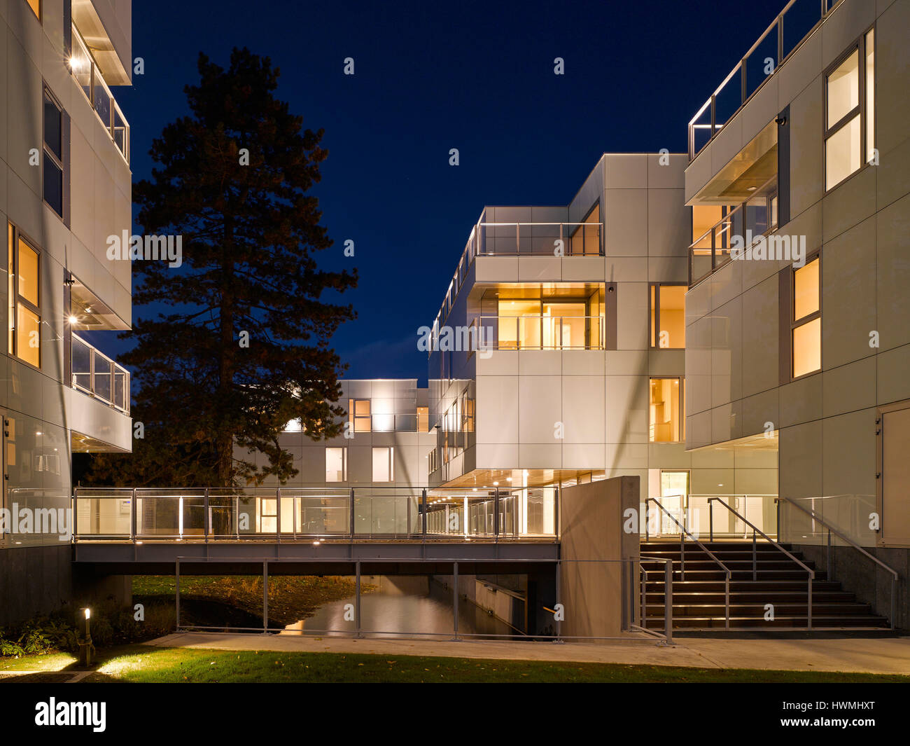 Nachtansicht von außen mit Treppe und Gehweg über Fluss. Dunluce Apartments, Ballsbridge, Irland. Architekt: Derek Tynan Architekten, 2016. Stockfoto