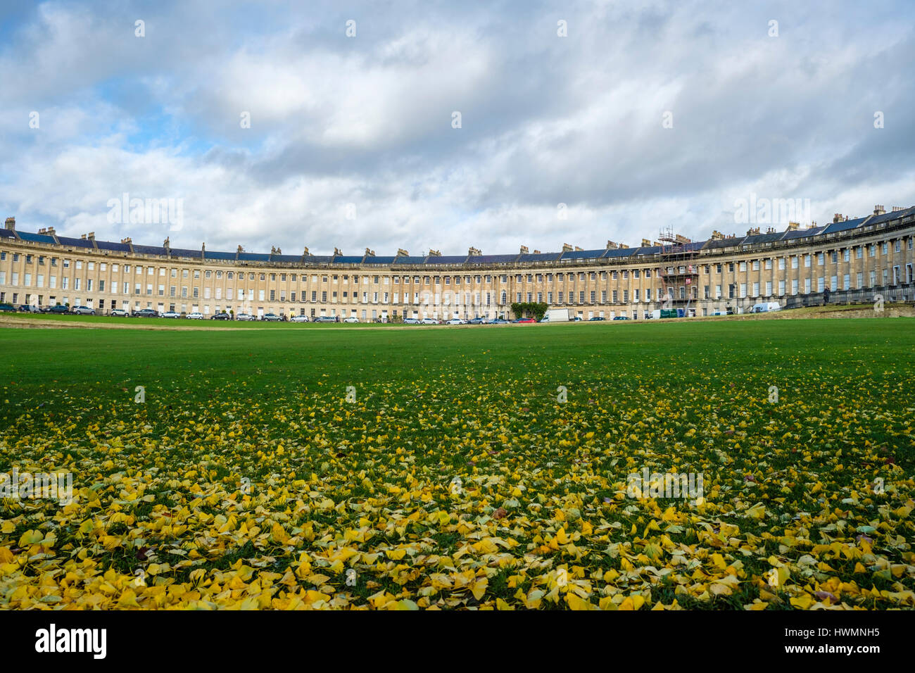 Herbstliche Laub auf dem Rasen vor der beeindruckenden Sweep georgianischer Architektur der Royal Crescent in Bath, England mit wolkig-Szene Stockfoto