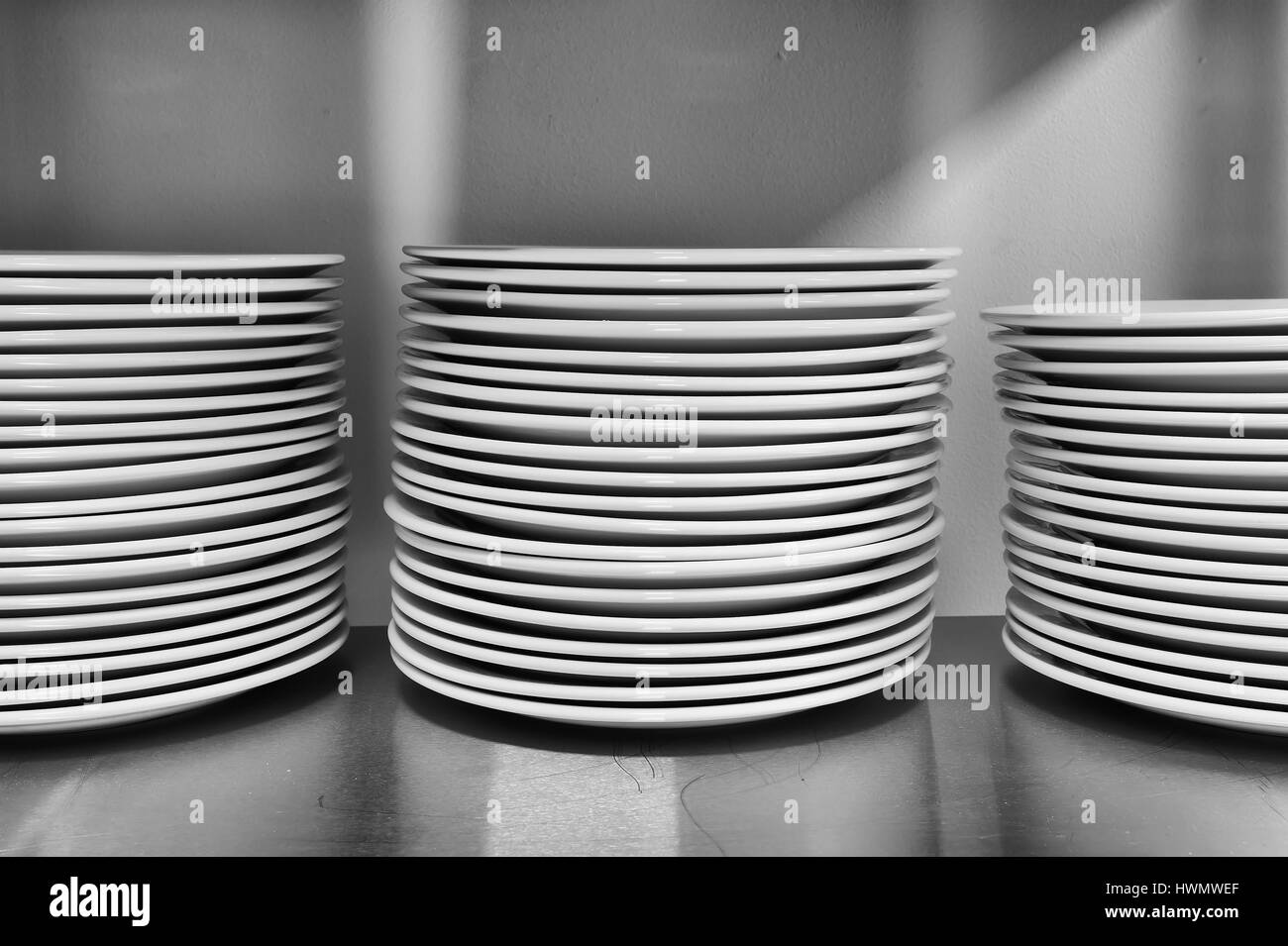 Stapel von weiß gewaschen runden Teller servieren auf einem Tisch in der Küche warten. Geschirr im Rahmen des modernen Komforts. Stockfoto