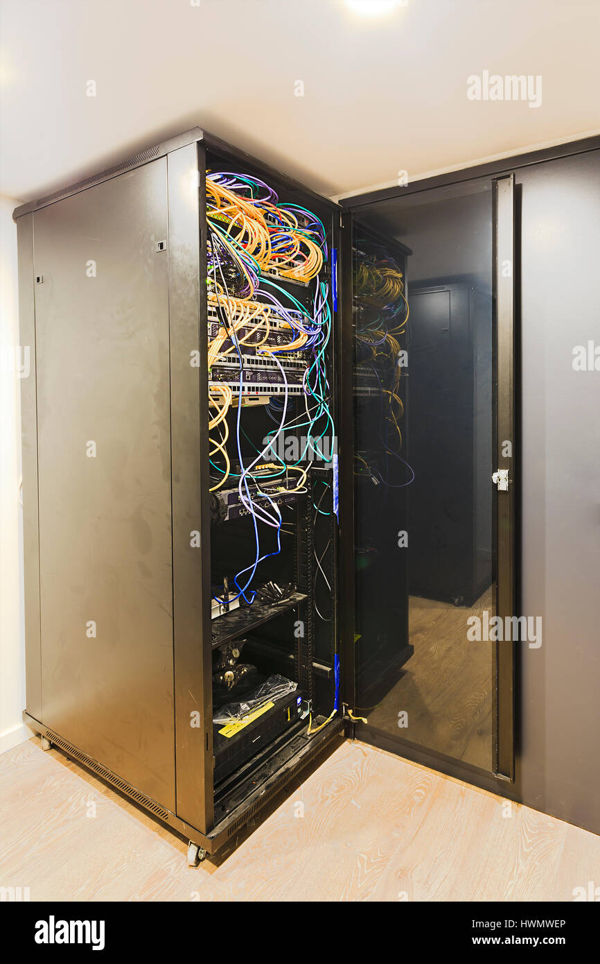 Ecke stehen allein Rack-Schrank mit Sicherheits-Tür in Kleinunternehmen Datenraum Zentrum mit offenen Patch-Panels und Kordeln. Stockfoto