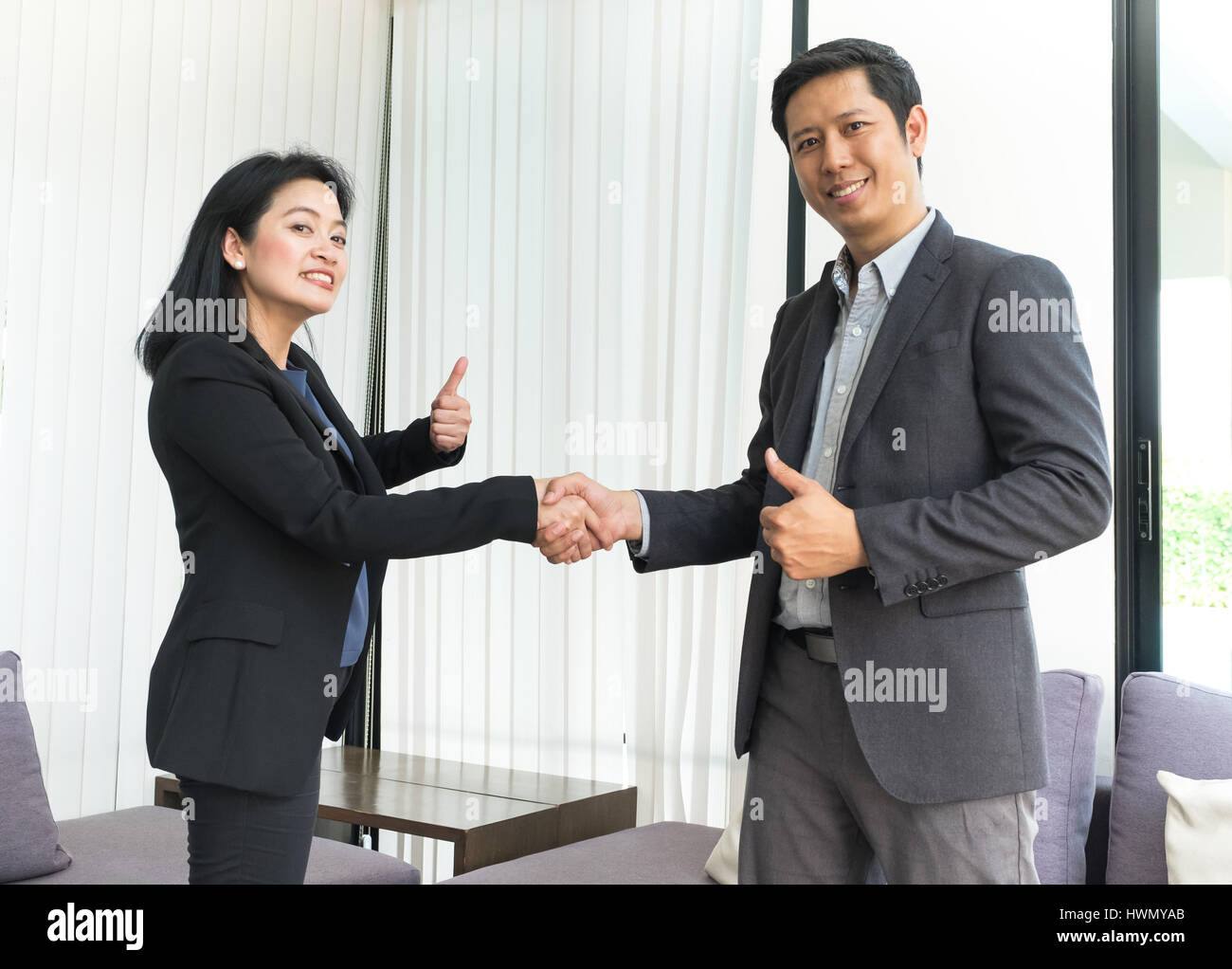 Lächeln Sie, Geschäftsfrau und Geschäftsmann schütteln von Hand und Daumen in Büro, Vereinbarung Partnerschaftskonzept. Stockfoto
