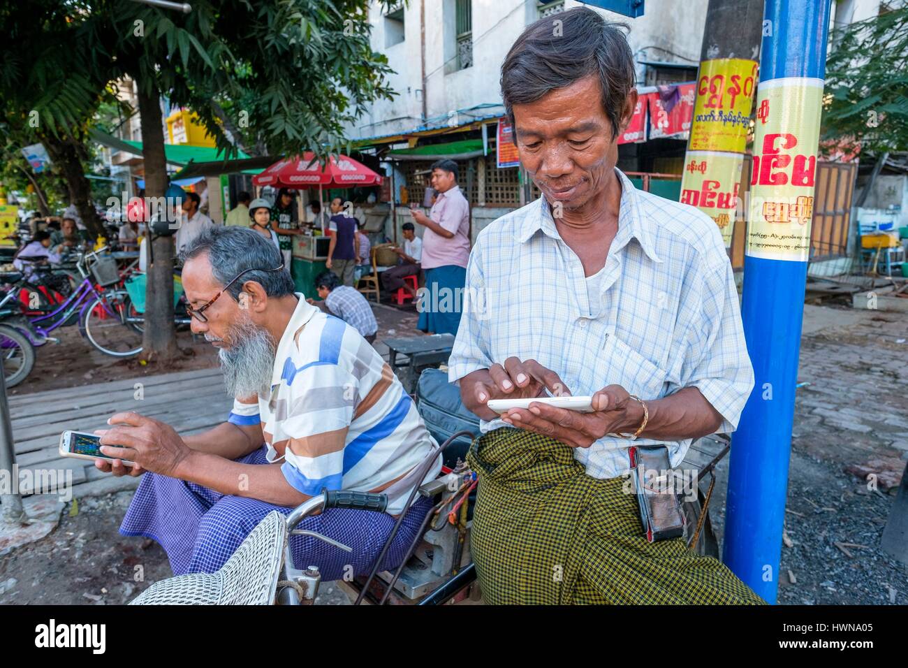 Myanmar (Burma), Mandalay Region, Mandalay, Fahrrad-Taxi-Fahrer mit ihrem Handy spielen Stockfoto