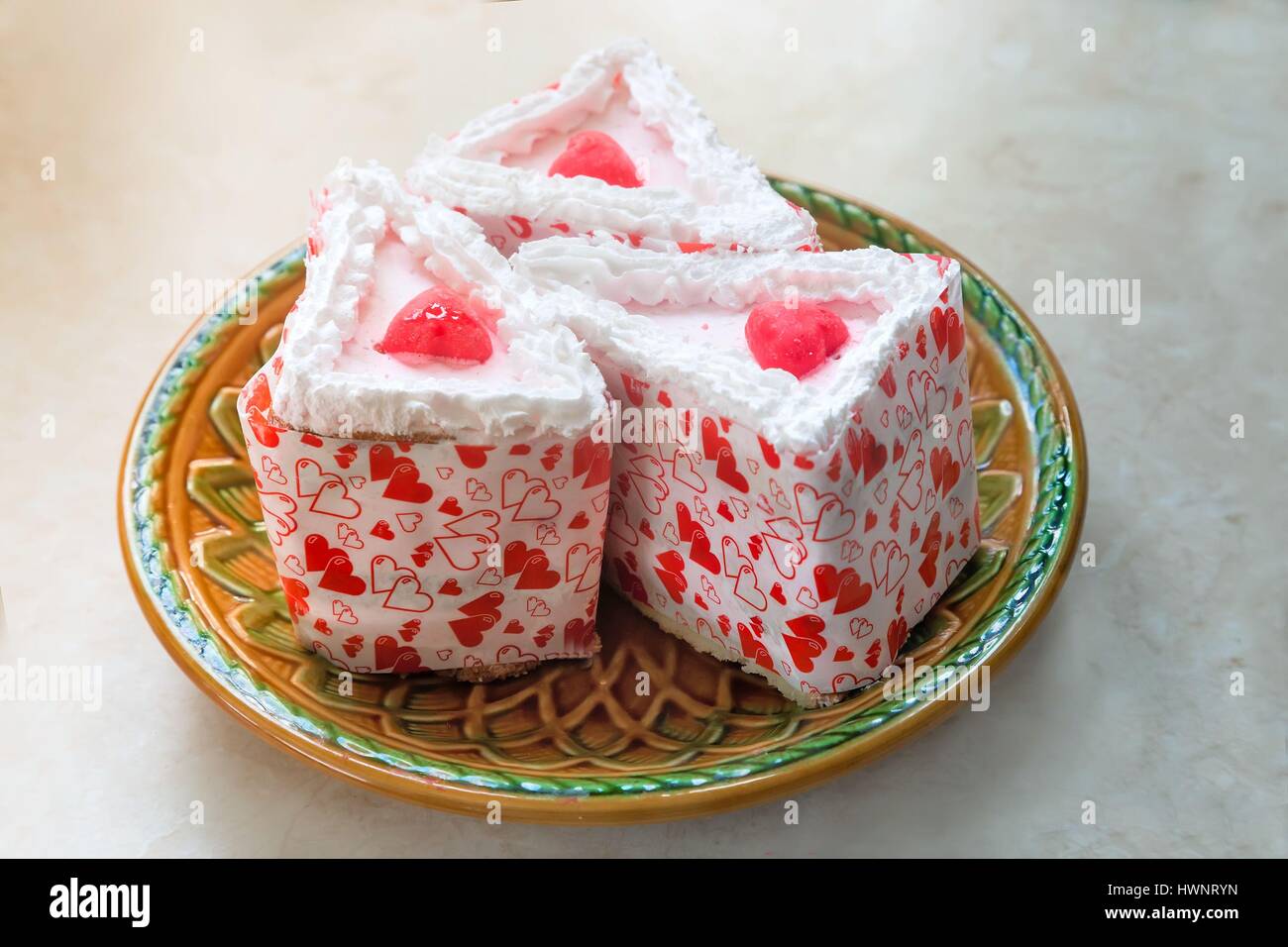 Auf dem Tisch in einer keramischen Platte liegen drei Stücke Kuchen verpackt in schönes Papier. Stockfoto