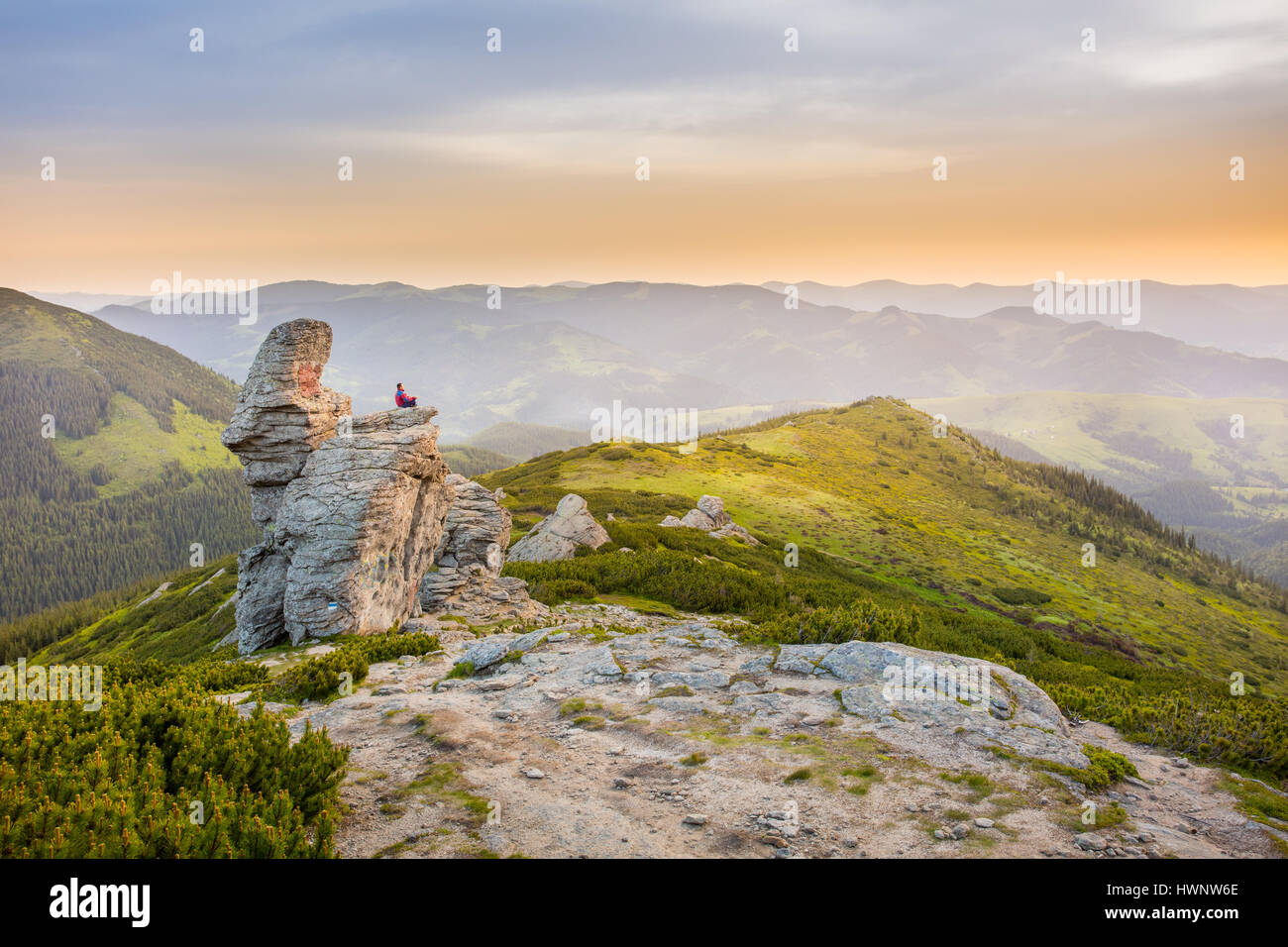 Mann meditiert auf einem Felsen in den Bergen. Stockfoto