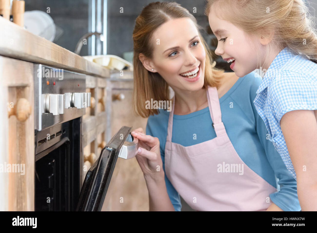 Glückliche Mutter und Tochter Eröffnung Ofen beim Kekse backen Stockfoto