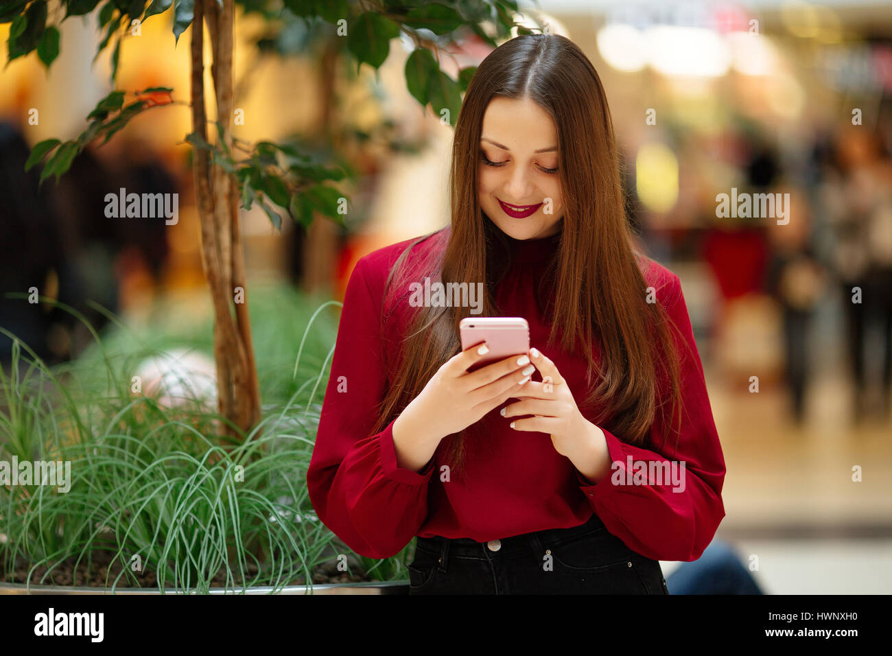 Brünette Frau sitzt auf der Straße und SMS auf dem Handy Stockfoto